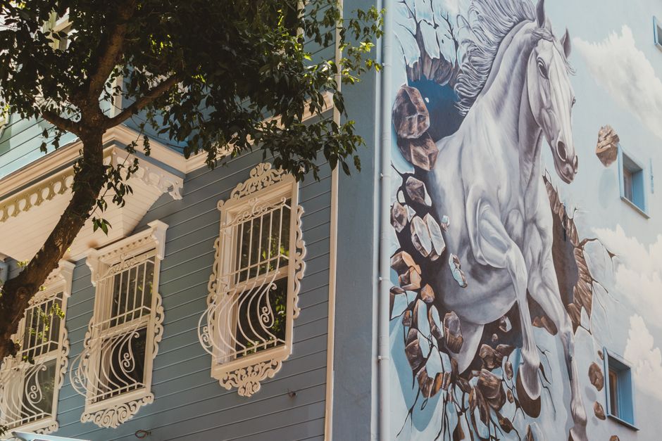 Blue painted house wall with ornate windows.